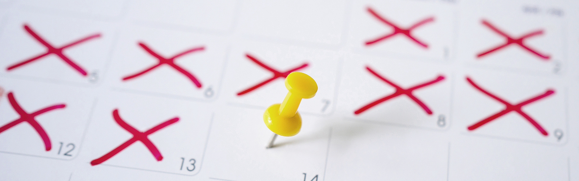 Kalender mit roten Kreuzen und gelbem Pin